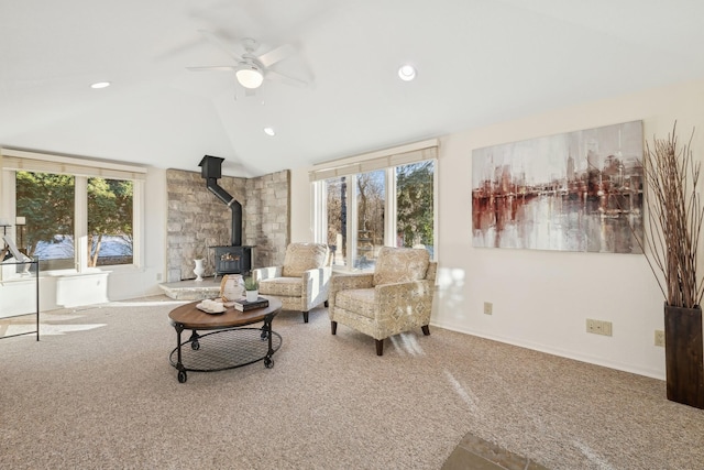 carpeted living room featuring ceiling fan, plenty of natural light, lofted ceiling, and a wood stove