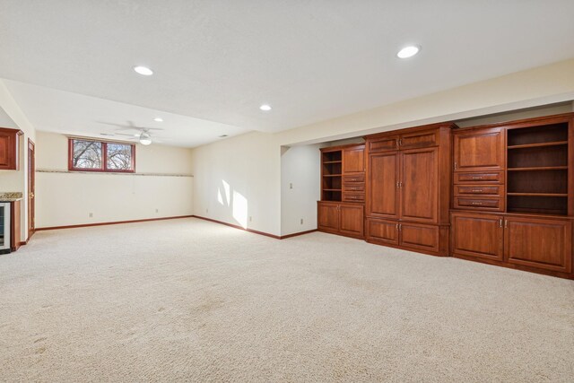 unfurnished living room with wine cooler, light colored carpet, and ceiling fan