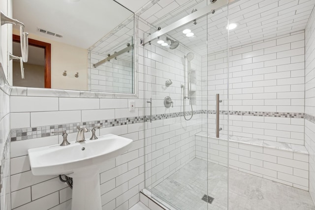 bathroom featuring a shower with door, tile walls, and backsplash