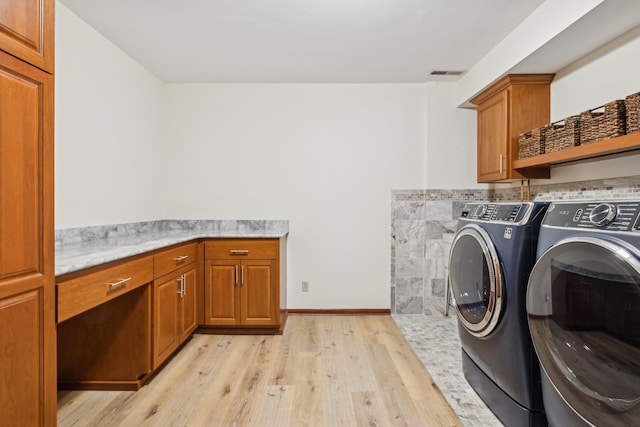 washroom with cabinets, separate washer and dryer, and light hardwood / wood-style flooring