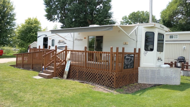 back of property featuring a wooden deck and a lawn