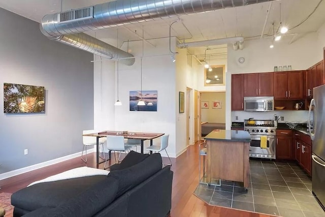 kitchen with appliances with stainless steel finishes, visible vents, dark brown cabinets, and a high ceiling