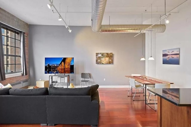 living area featuring rail lighting, baseboards, and wood finished floors