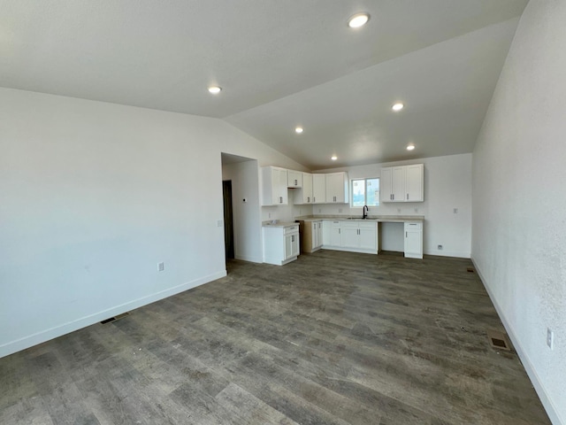 unfurnished living room featuring a sink, visible vents, lofted ceiling, and baseboards