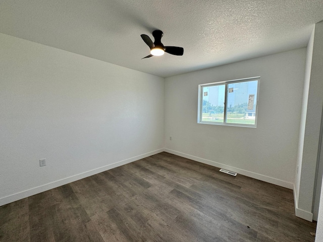 empty room with baseboards, dark wood-type flooring, a ceiling fan, and a textured ceiling