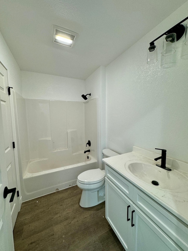 bathroom featuring vanity, wood finished floors, visible vents, tub / shower combination, and toilet