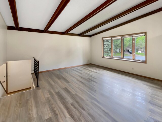 spare room with light wood-type flooring and vaulted ceiling with beams