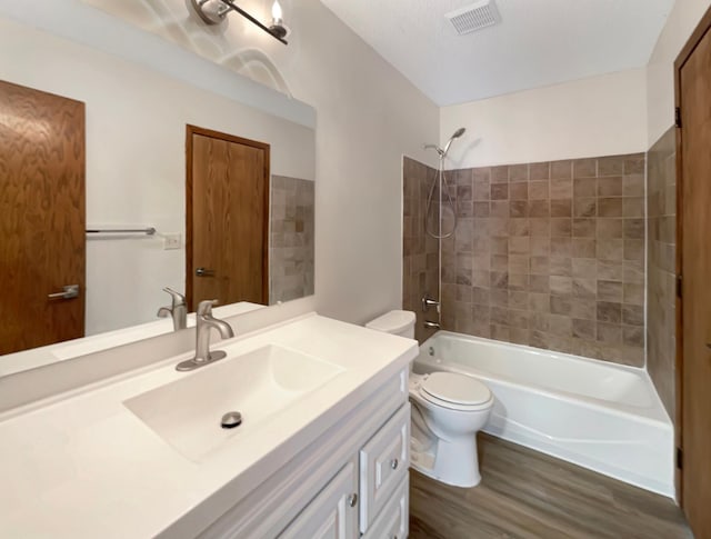 full bathroom with vanity, toilet, tiled shower / bath, and hardwood / wood-style flooring