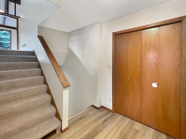 stairway featuring light hardwood / wood-style floors and a textured ceiling