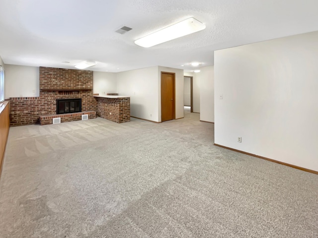 unfurnished living room with a textured ceiling, a brick fireplace, and light colored carpet