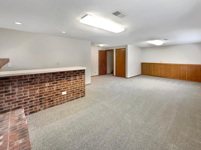 basement with a textured ceiling and light colored carpet