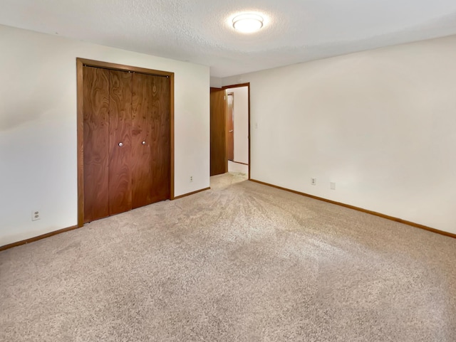 unfurnished bedroom featuring light colored carpet, a closet, and a textured ceiling