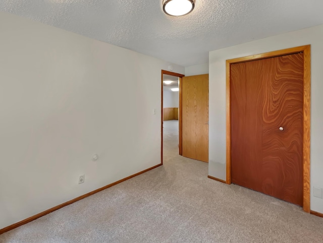 unfurnished bedroom featuring a textured ceiling and light colored carpet