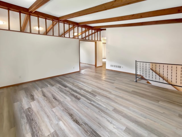 spare room featuring vaulted ceiling with beams and hardwood / wood-style floors