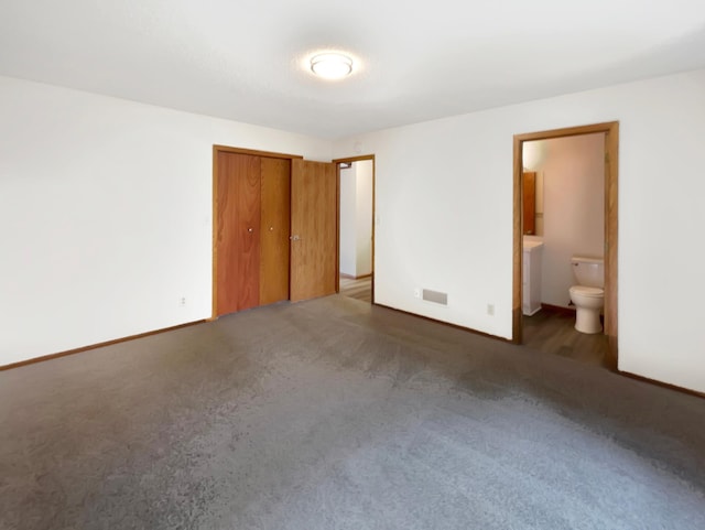 unfurnished bedroom with dark colored carpet and connected bathroom