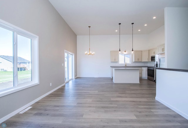 kitchen featuring a notable chandelier, stainless steel appliances, open floor plan, recessed lighting, and a towering ceiling