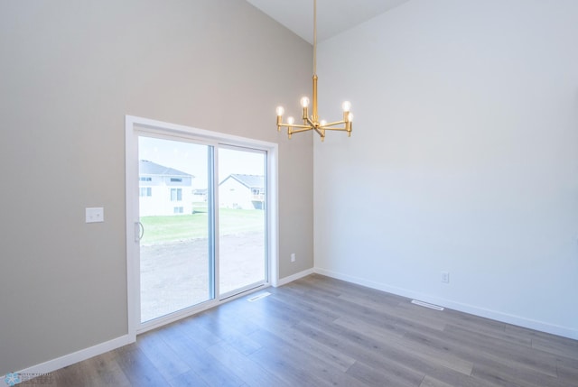 interior space with visible vents, wood finished floors, baseboards, high vaulted ceiling, and a chandelier