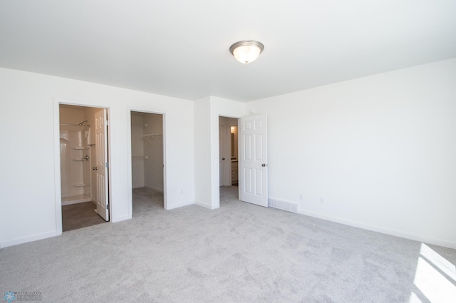 unfurnished bedroom featuring carpet floors, baseboards, a spacious closet, visible vents, and a closet
