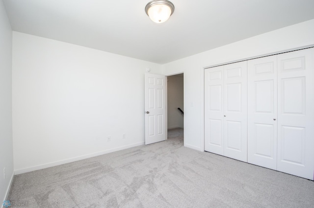 unfurnished bedroom featuring baseboards, carpet, and a closet