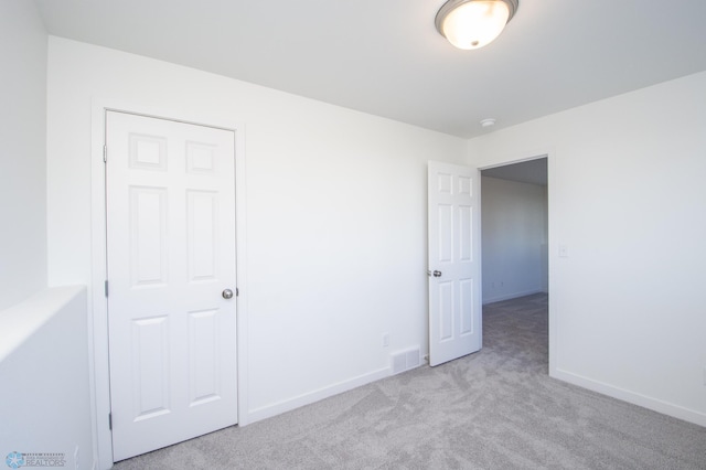 unfurnished bedroom with baseboards, visible vents, and carpet
