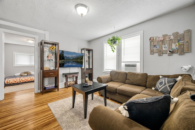 living room with light hardwood / wood-style floors, cooling unit, and a textured ceiling