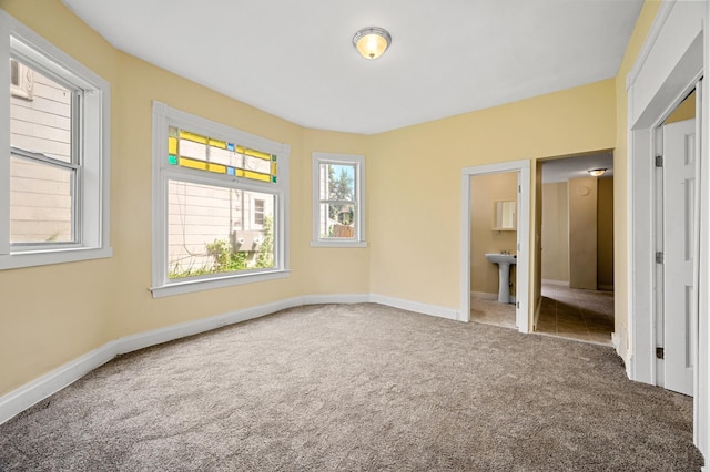 unfurnished bedroom with ensuite bathroom, carpet flooring, and sink