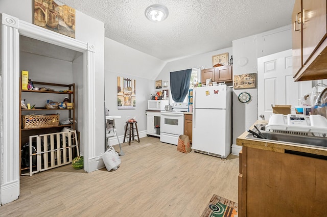 kitchen with light hardwood / wood-style flooring, a textured ceiling, white appliances, and vaulted ceiling