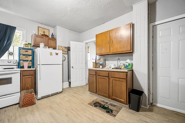 kitchen featuring white appliances, a textured ceiling, sink, and light hardwood / wood-style flooring