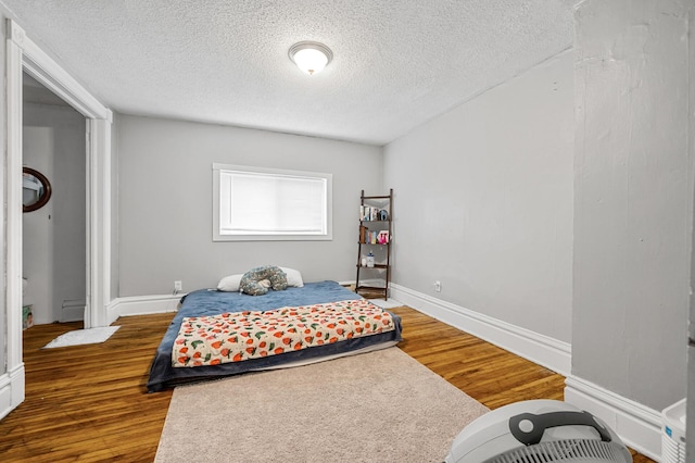 bedroom featuring dark wood-type flooring, baseboard heating, and a textured ceiling