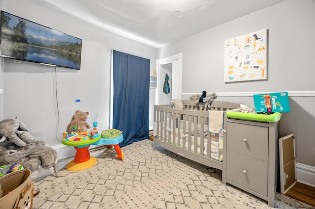 bedroom with light hardwood / wood-style floors and a crib