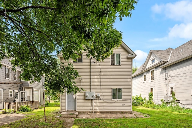 back of property featuring a wooden deck and a lawn