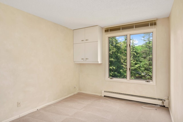 carpeted empty room with a baseboard heating unit and a textured ceiling