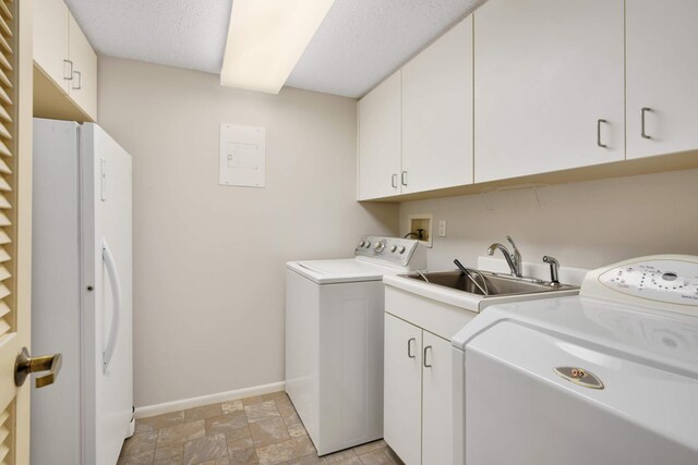 washroom with cabinets, a textured ceiling, sink, and washing machine and clothes dryer