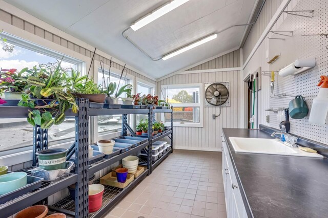 kitchen with wood walls, vaulted ceiling, white cabinets, and plenty of natural light