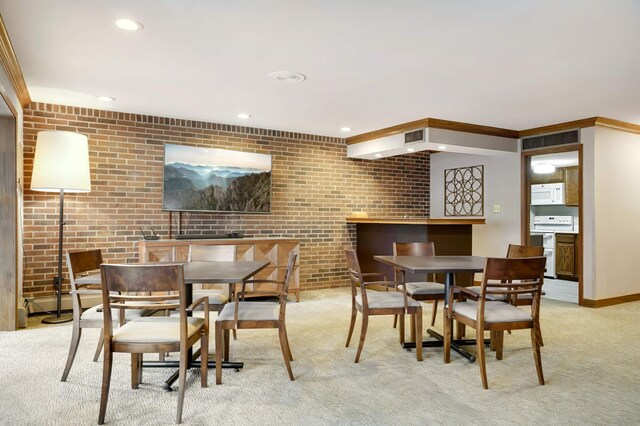 carpeted dining room with brick wall and ornamental molding