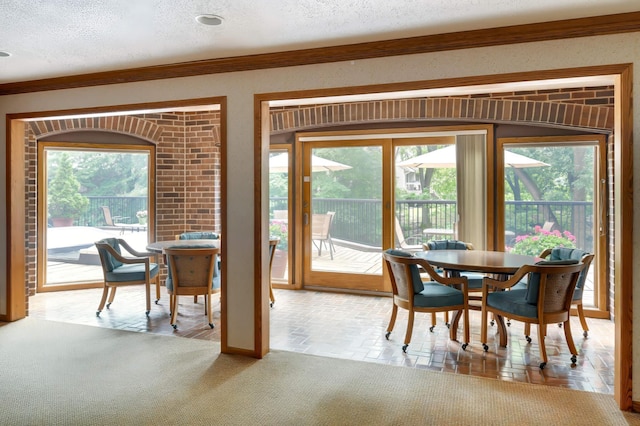 dining room featuring crown molding, a textured ceiling, and plenty of natural light