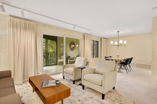 carpeted living room featuring track lighting and an inviting chandelier