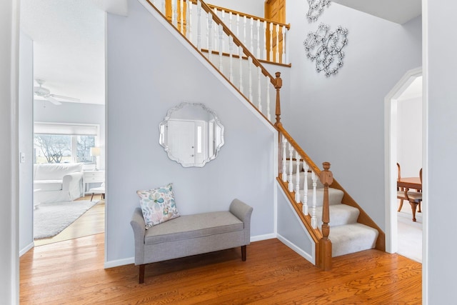 stairs featuring wood finished floors, baseboards, and ceiling fan