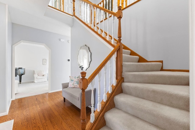 stairs featuring baseboards, arched walkways, and wood finished floors