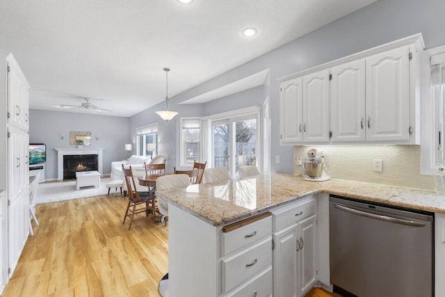 kitchen with open floor plan, dishwasher, a lit fireplace, a peninsula, and white cabinetry