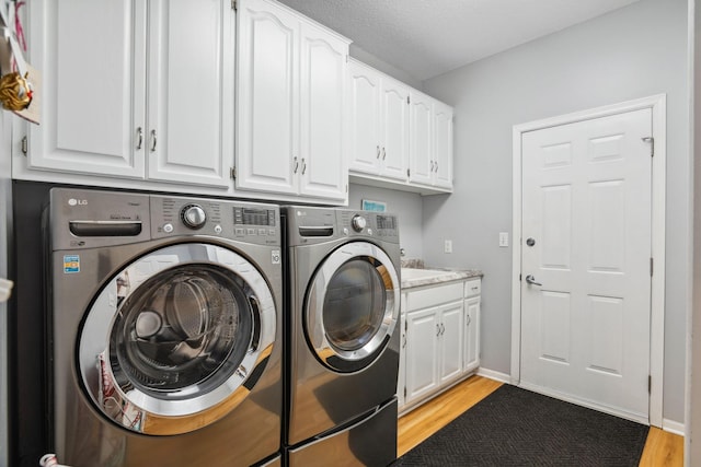 laundry area featuring washer and dryer, baseboards, cabinet space, and light wood-style floors