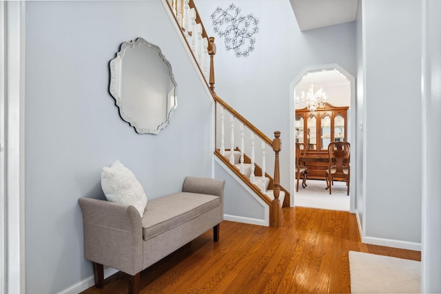 interior space featuring baseboards, arched walkways, wood finished floors, and stairs