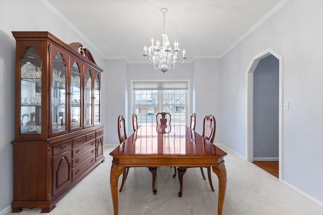 dining room featuring a notable chandelier, arched walkways, light colored carpet, and crown molding