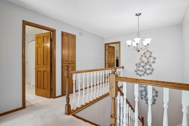 hallway with an inviting chandelier, an upstairs landing, light colored carpet, and baseboards