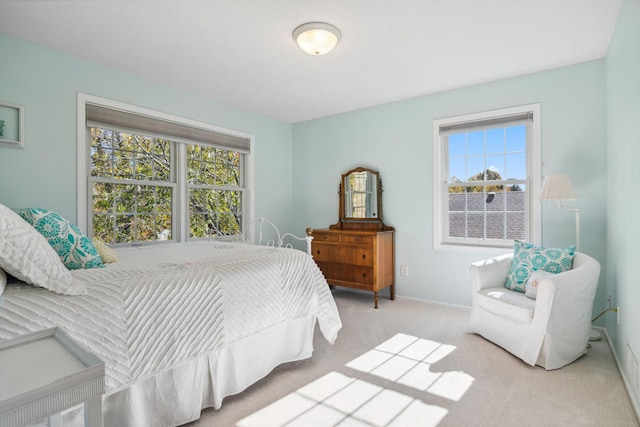 bedroom with multiple windows, light colored carpet, and baseboards