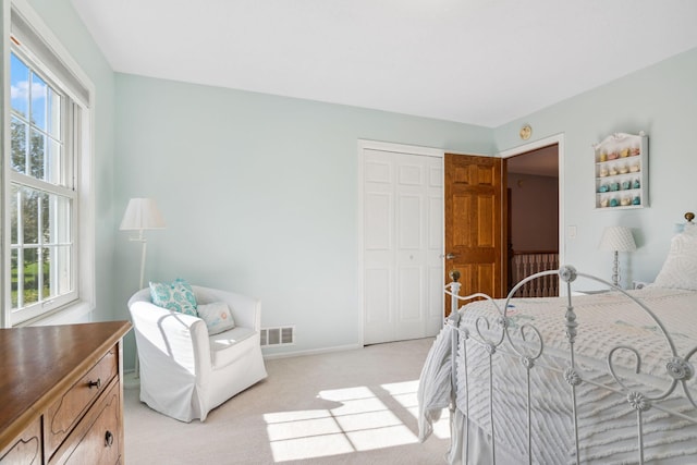 bedroom featuring baseboards, visible vents, light carpet, and a closet