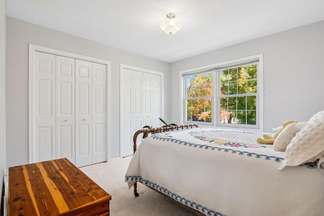 bedroom with light colored carpet and two closets