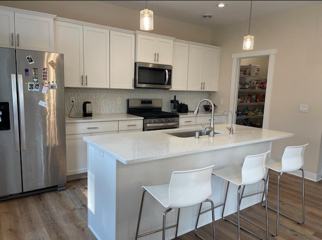 kitchen with sink, appliances with stainless steel finishes, white cabinetry, and an island with sink