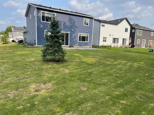 rear view of property featuring a patio area, central AC, and a lawn