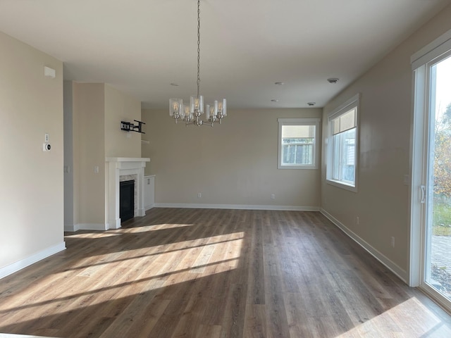 unfurnished living room featuring a notable chandelier and dark hardwood / wood-style flooring